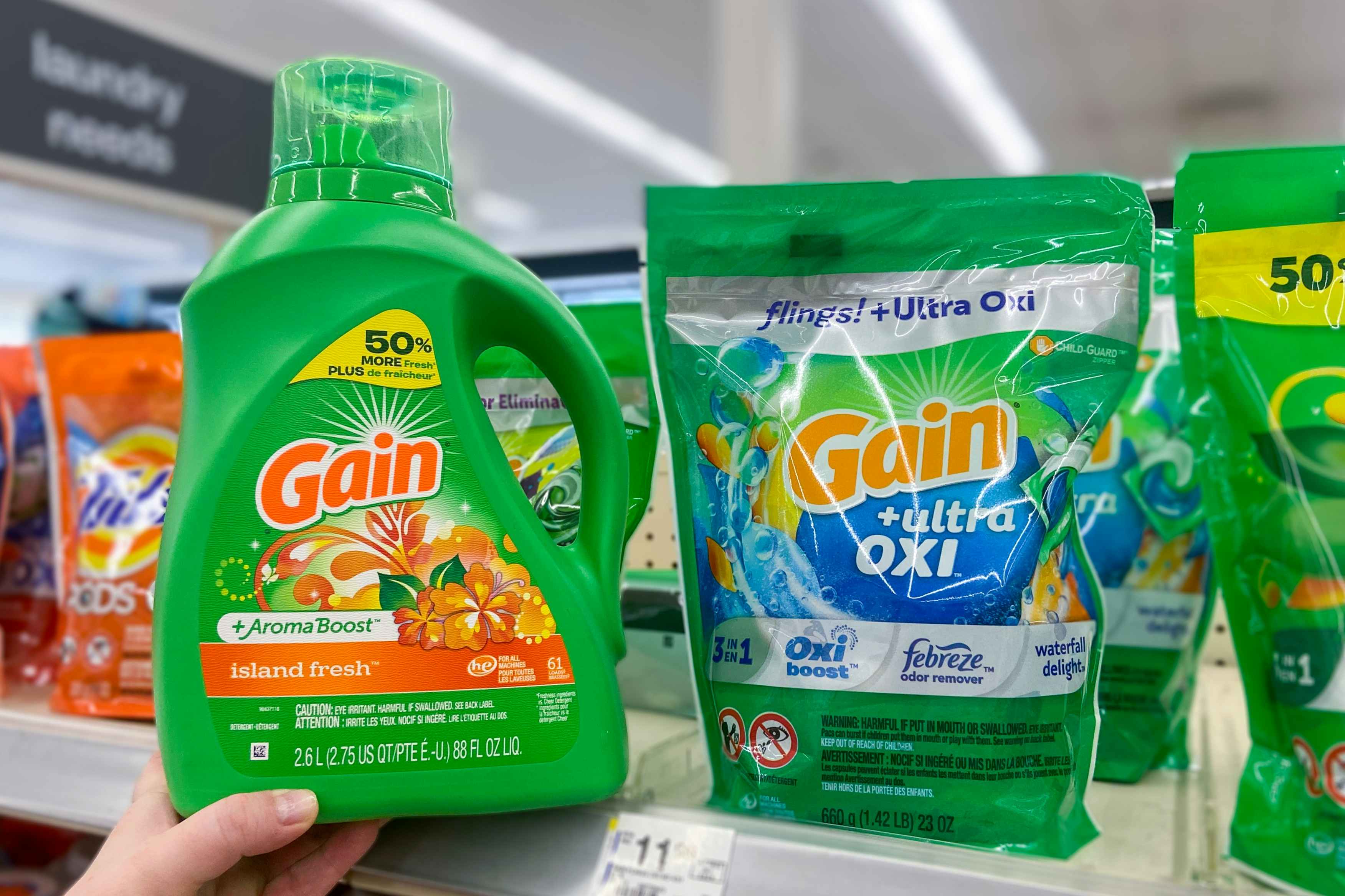 hand holding a large bottle of gain laundry detergent next to gain flings on a shelf