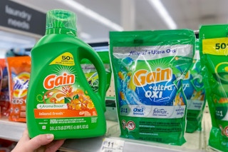 hand holding a large bottle of gain laundry detergent next to gain flings on a shelf