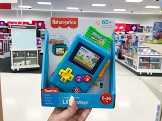 hand holding a fisher-price laugh & learn lil' gamer at target