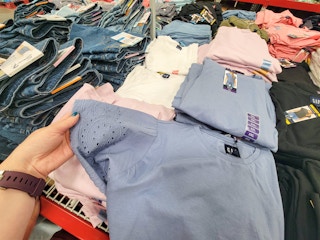 hand holding a blue top with eyelet sleeves