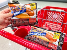 hand holding one Ball Park Franks pack next to another in shopping cart