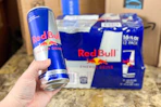 a woman holding a can of red bull