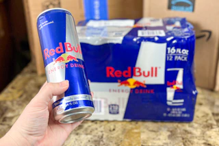 a woman holding a can of red bull