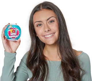 A girl holding a 5 Surprise toy capsule.