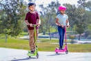 Two kids' riding Razor electric scooters in green and pink outdoors (lifestyle image)