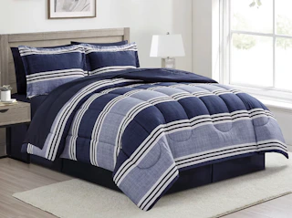 a bed with a blue and white comforter set in a room