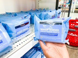 A hand holding Neutrogena makeup wipes in a store aisle.