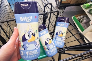 person holding a bottle of bluey body wash with 2 more bottles in a cart