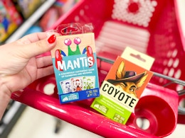 hand holding an exploding kittens game over a target cart