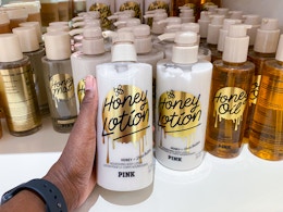 someone holding body lotion in front of a display of body care items on a shelf