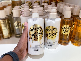 someone holding body lotion in front of a display of body care items on a shelf