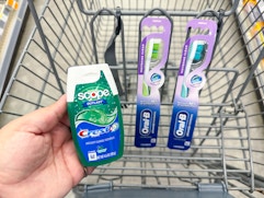 hand holding crest and two oral-b products in walgreens cart
