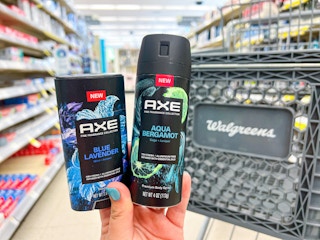 Someone holding Axe Blue Lavender deodorant stick and Aqua Bergamot body spray in Walgreens