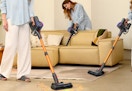people cleaning a room and couch with cordless stick vacuums
