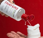 a hand pouring toner into cotton pads