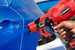a cordless paint sprayer spraying on a car