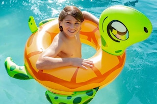 a kid in a swimming pool with a turtle tube