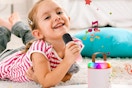 B0FNW88Y5G Mini Karaoke Machine little girl on rug lying on stomach singing into microphone