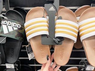 hand holding tan adidas slides