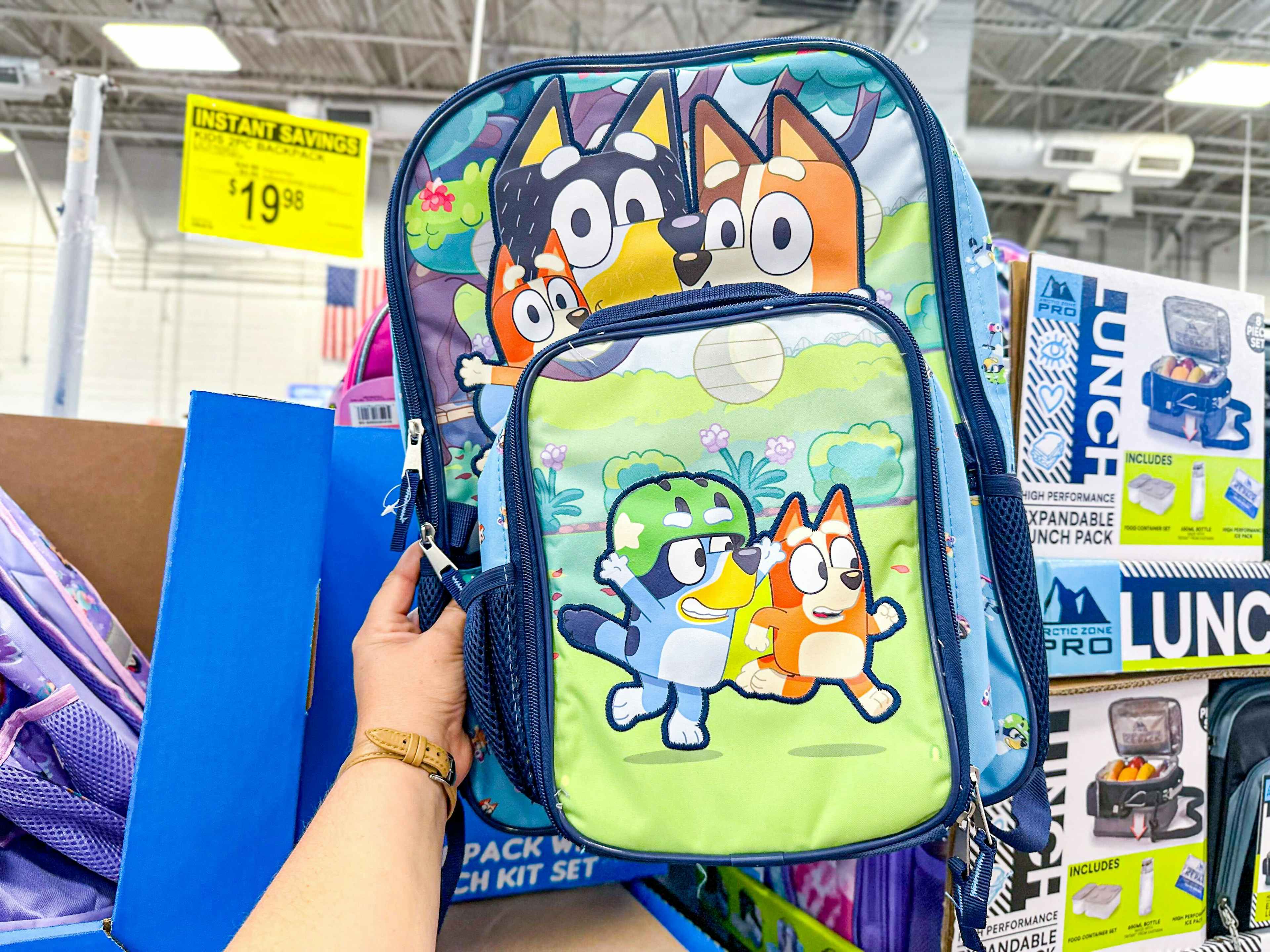 person holding a bluey backpack and lunch box set