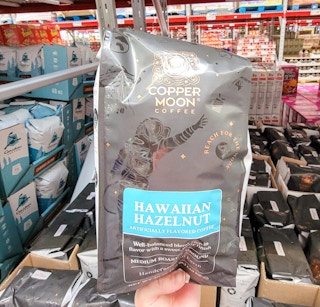 hand holding a 40 oz bag of copper moon hawaiian hazelnut coffee grounds