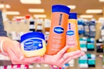 hands holding vaseline healing jelly ointment, shimmering body oil, and cocoa radiant lotion
