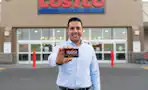 a man holding a costco card in front of the store