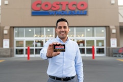 a man holding a costco card in front of the store