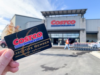 A costco membership held in front of a costco store front