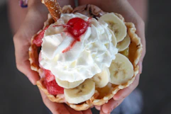 a person holding a banana split sundae
