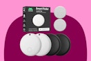 Four round Android tracker tags, 2 black and two white with a black and white box, plus two extra watch-type batteries