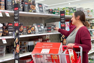 woman with a target shopping cart grabbing rubbermaid off a shelf