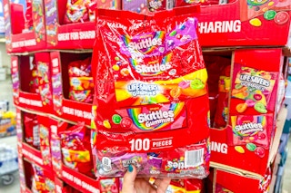 person holding a large bag of skittles and life savers gummer candy