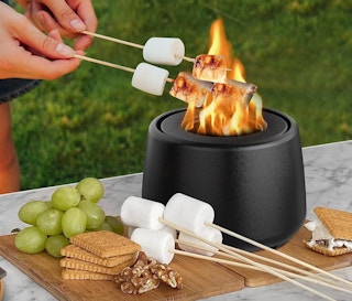 someone roasting marshmallows over a mini fire pit