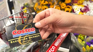 a person holding a costco card in front of cart