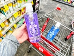 person holding a bottle of safeguard hand soap over a cart with another bottle in it