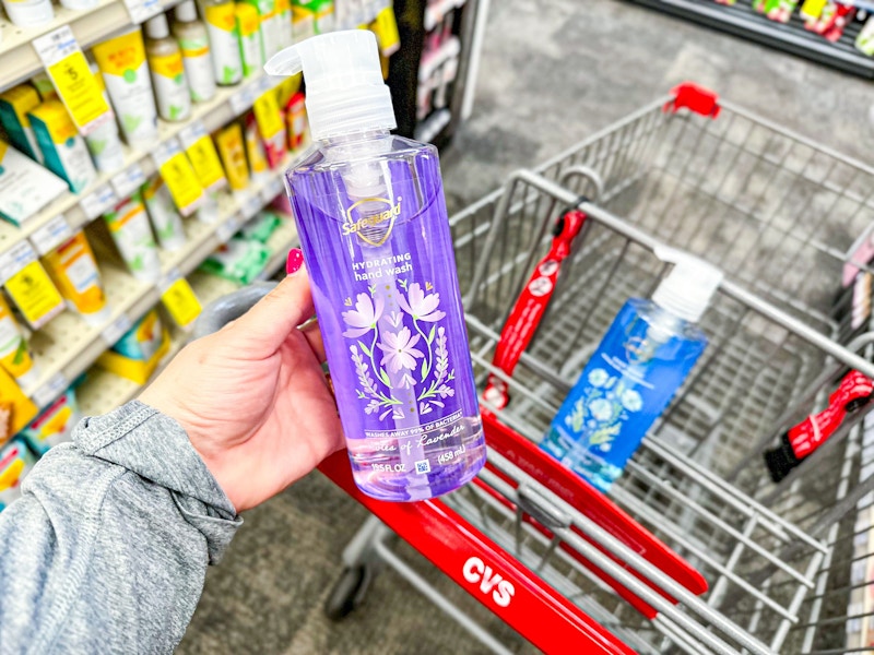 person holding a bottle of safeguard hand soap over a cart with another bottle in it