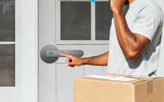a person with a box at a door with a fingerprint door lock