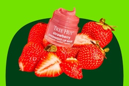 A Tree Hut Overnight Lip Mask in strawberry flavor among a bunch of strawberries