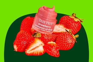 A Tree Hut Overnight Lip Mask in strawberry flavor among a bunch of strawberries