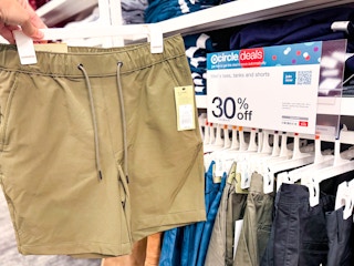 Men's shorts at Target held in front of 30% off sale sign
