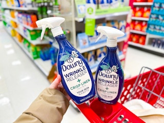 hand holding a downy wrinkle releaser spray in front of target cart