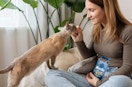 a woman giving her cat a cat treat