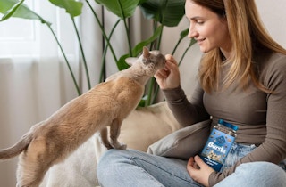 a woman giving her cat a cat treat