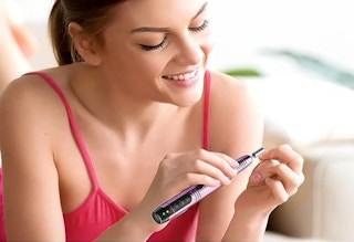 a woman doing her nails with a nail drill