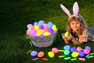 Lifestyle image of child laying on the grass with glowing Easter eggs