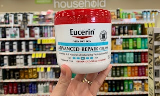 A hand holding a container of Eucerin lotion.