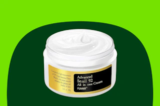 A jar of white snail mucin moisturizing cream all in one, missing the lid, for skin renewal.