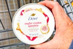hand holding a jar of dove body scrub