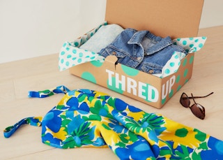 thredup box with jean jacket in it and with dress next to it